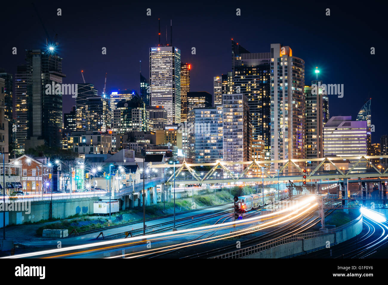 Blick auf Eisenbahnschienen und modernen Gebäuden in der Innenstadt in der Nacht, von der Bathurst Street Bridge in Toronto, Ontario. Stockfoto