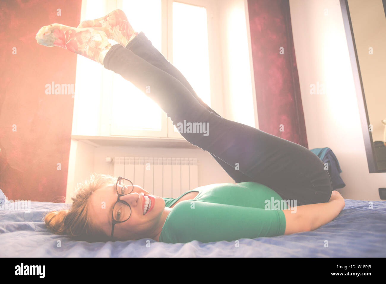 Übungen auf einem Sonntag Bett. Reportageaufnahme einer jungen Frau, Übungen und Entspannung auf dem Bett. Stockfoto