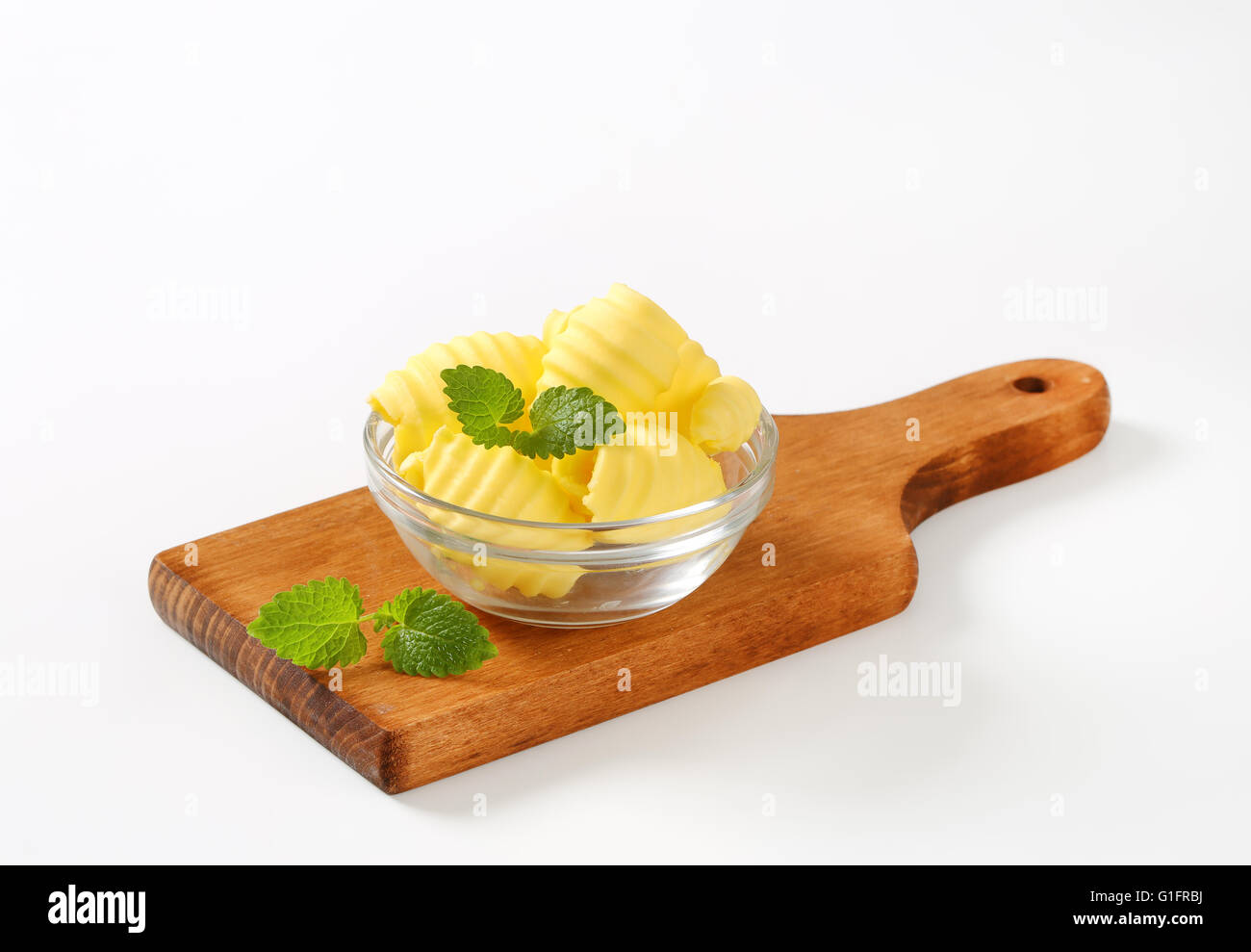 Schüssel mit Butter locken mit Minze auf Holzbrett Stockfoto