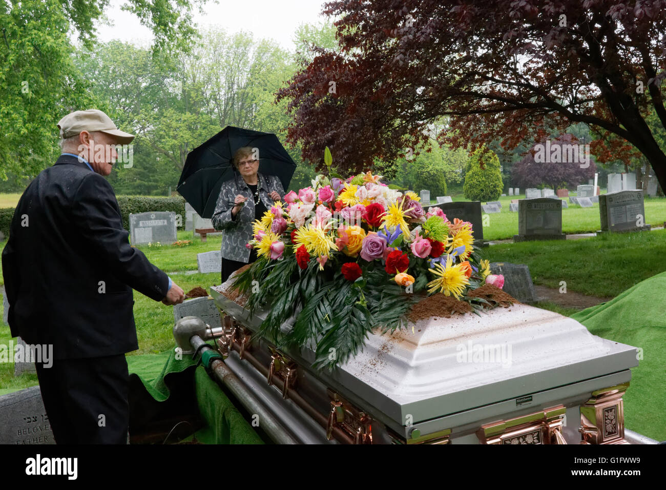 Während einer jüdischen Beerdigung in Upper Darby, Pennsylvania stellt ein Mann eine Schaufel voll von Schmutz an den Sarg. Stockfoto