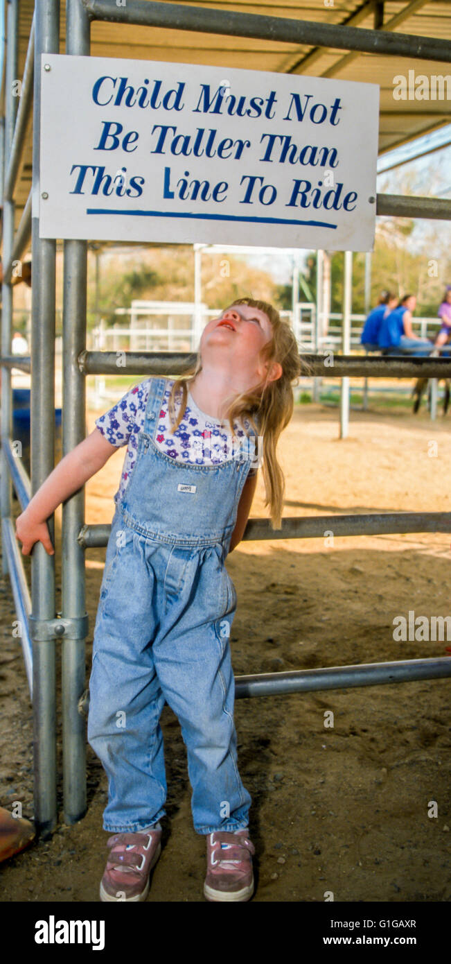 3 Jahre altes Mädchen blickte Überprüfung Zeichen für Höhe Qualifikation für Pony reiten. © Myrleen Pearson Stockfoto