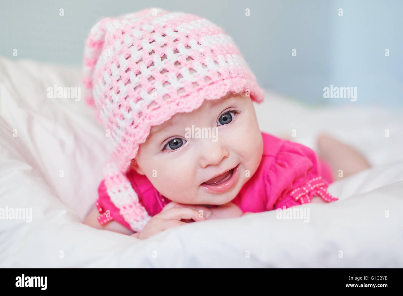 Neugeborenes Babymädchen in Rosa Mütze auf dem Bett Stockfoto