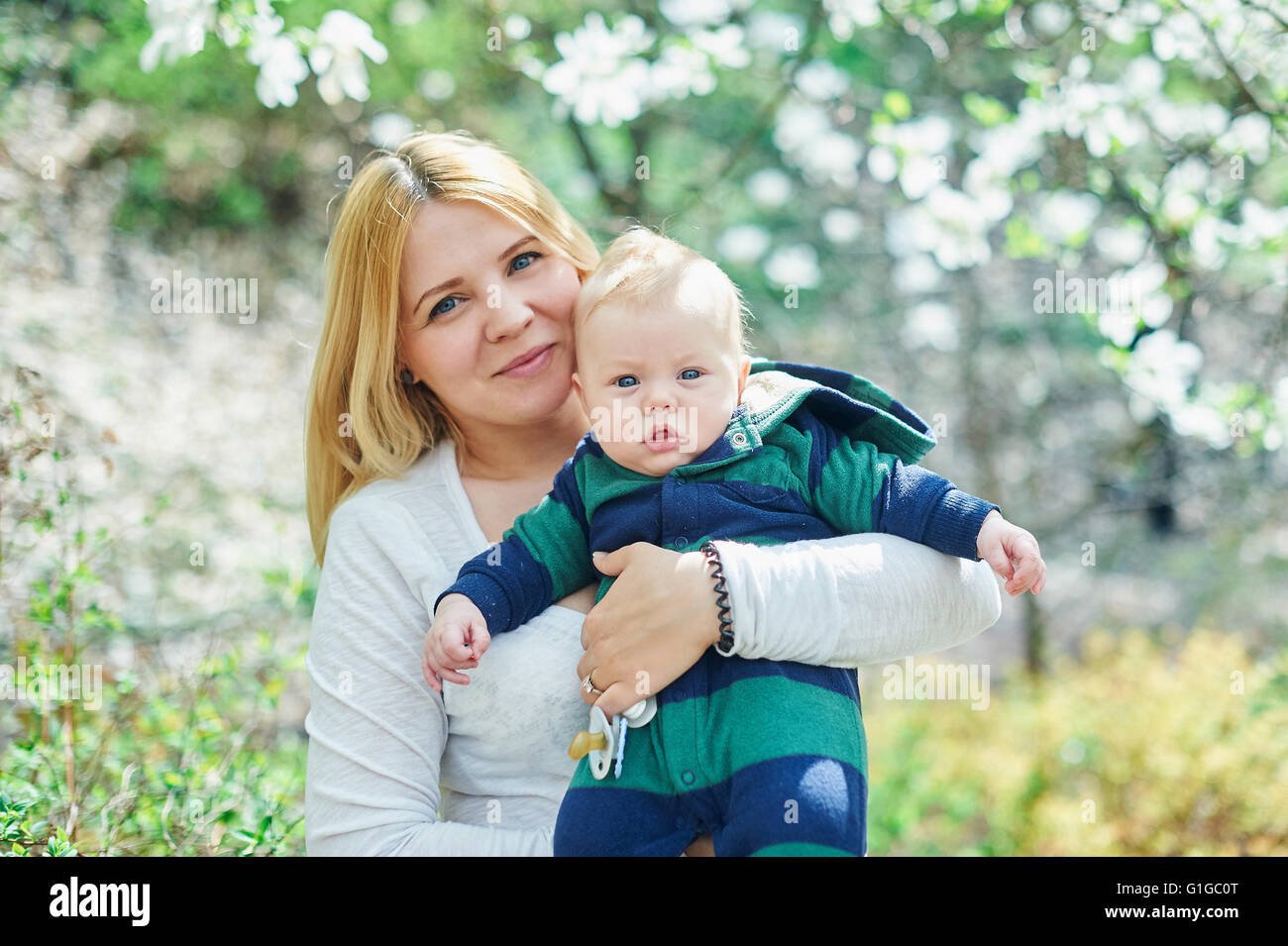 Mutter zu Fuß mit ihrem Baby Sohn im Garten des blühenden Magnolien Stockfoto