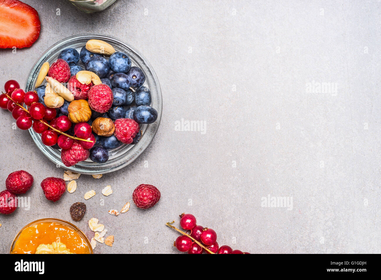 Frischen Sommerbeeren und Muttern auf grauem Stein Hintergrund, Ansicht von oben.  Gesundes Essen und sauberes Essen Konzept Stockfoto