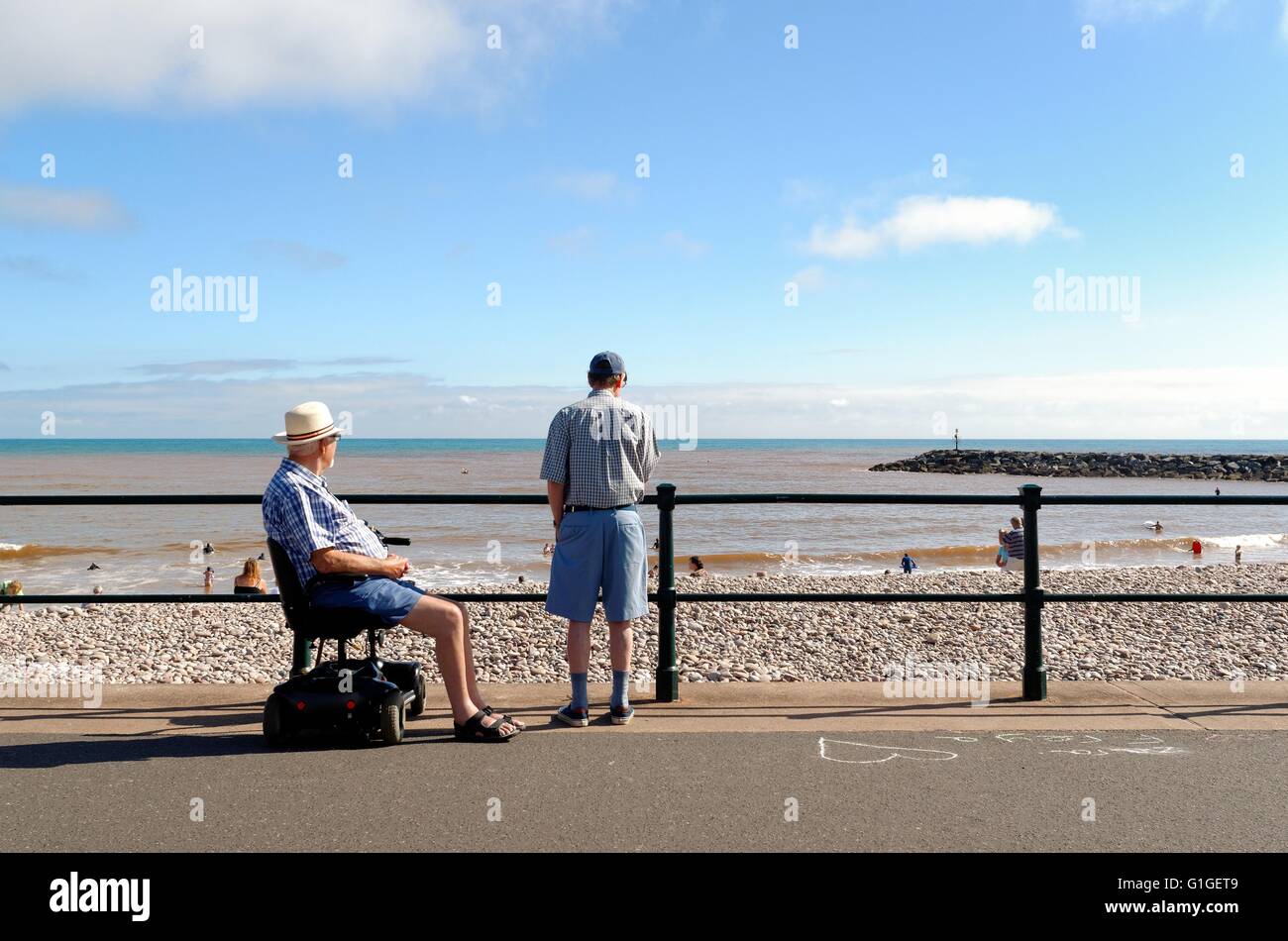 Ältere Herren, einer in einer Mobilität scooter mit Blick auf das Meer im Sommer am Meer Sidmouth Stockfoto