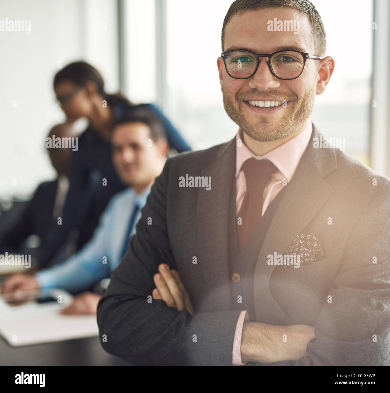 Lächelt zuversichtlich Geschäftsmann mit Brille Stand mit verschränkten Armen in die Kamera schaut Nahaufnahme mit Kollegen wor Stockfoto