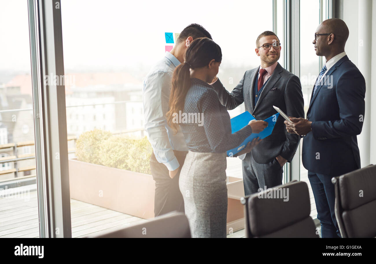 Multiethnische Business Team stehen vor einem Fenster in einem Konferenzraum im Büro mit einer Diskussion, Sonne Streulicht und co Stockfoto