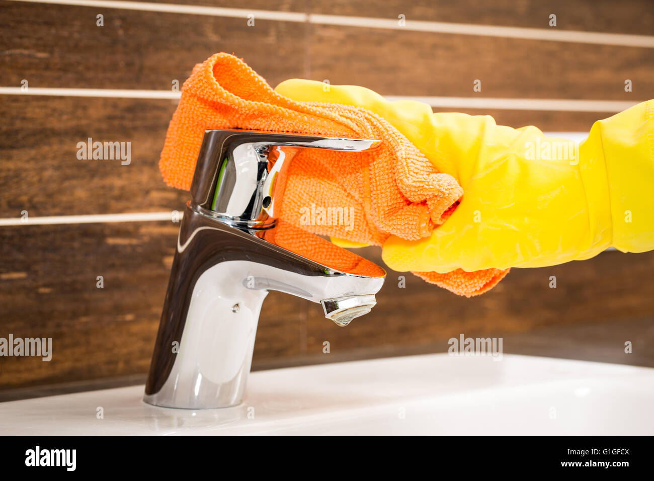 Frau tun Hausarbeiten im Badezimmer, moderne Wasserhahn reinigen. Stockfoto