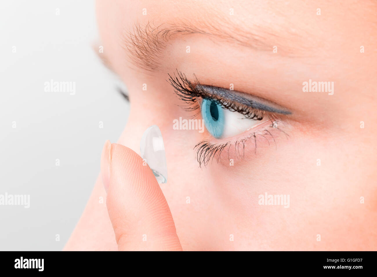 Frau einfügen eine Kontaktlinse im Auge. Stockfoto