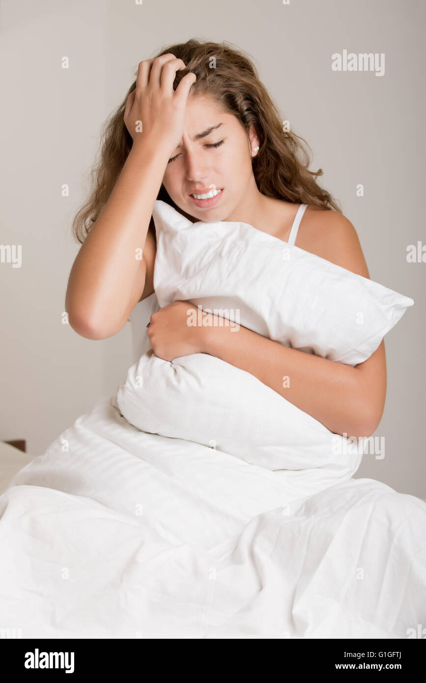 Frau sitzt auf einem Bett, aufwachen, isoliert in weiß Stockfoto