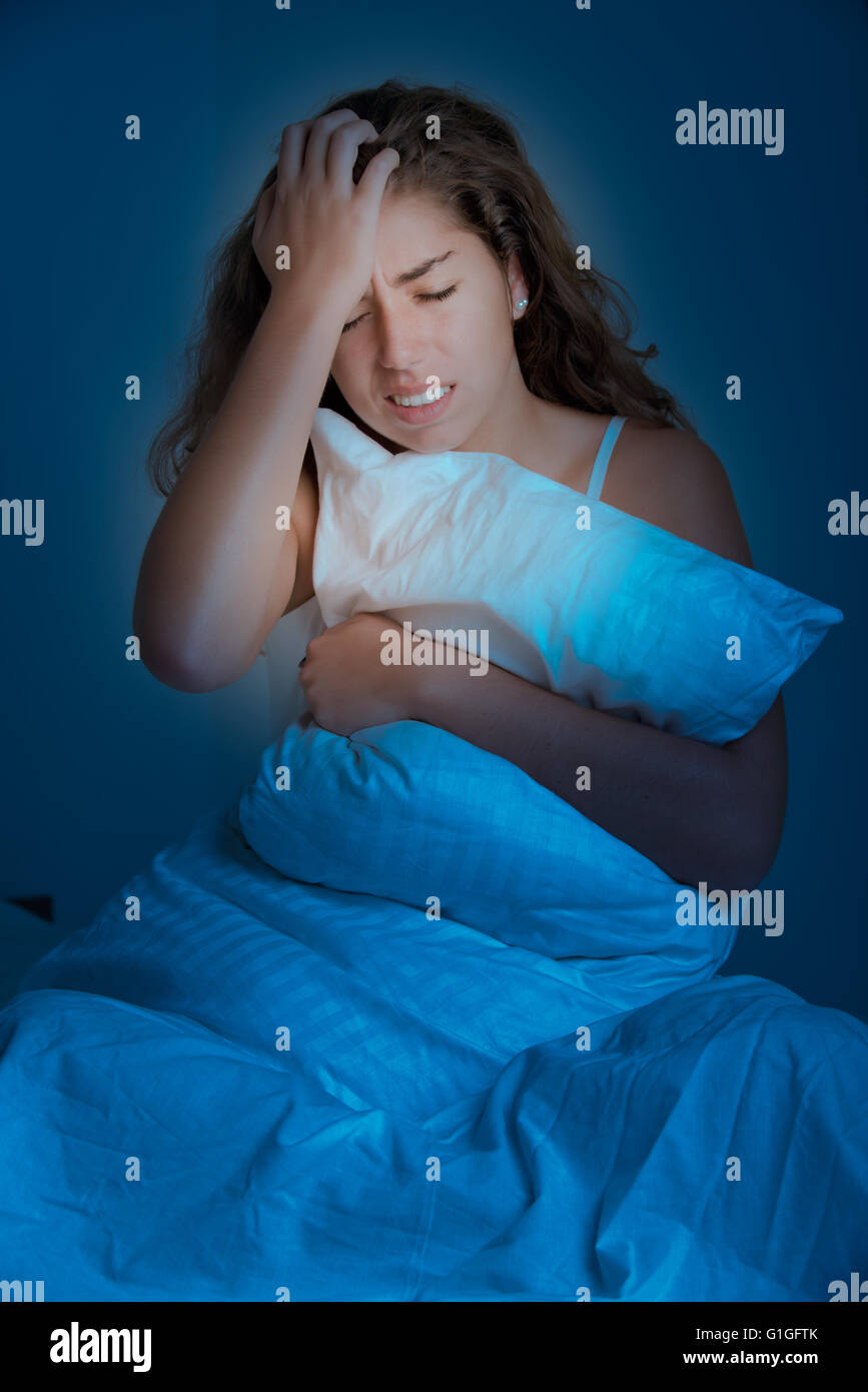 Frau sitzt auf einem Bett aufwachen, in der Dunkelheit Stockfoto