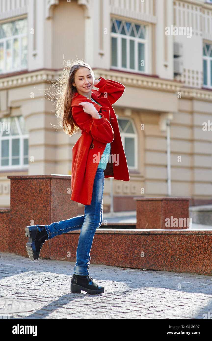 junge schöne Frau im roten Mantel in der Stadt Stockfoto
