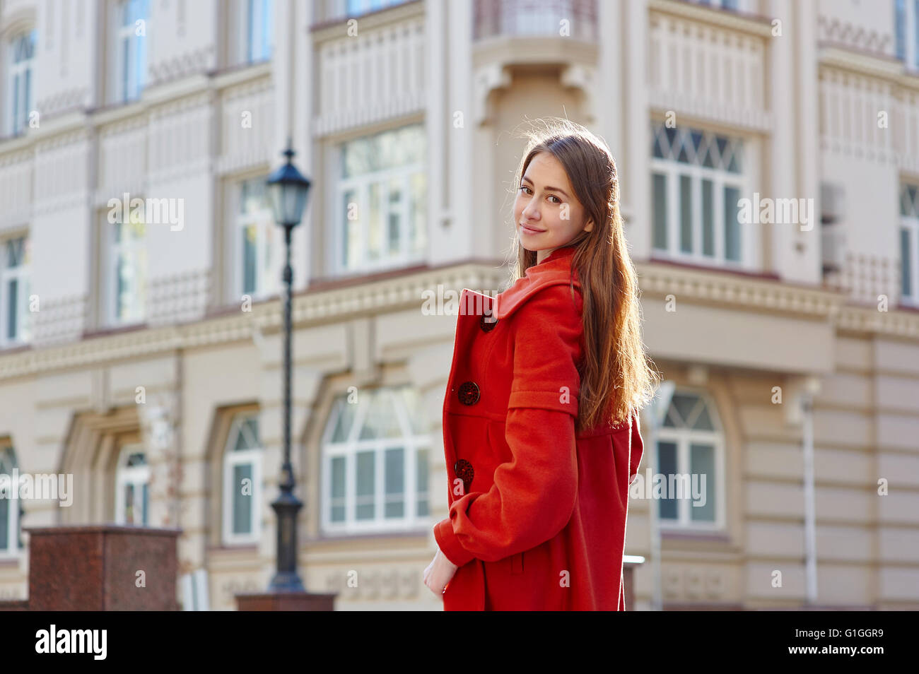 junge schöne Frau im roten Mantel in der Stadt Stockfoto