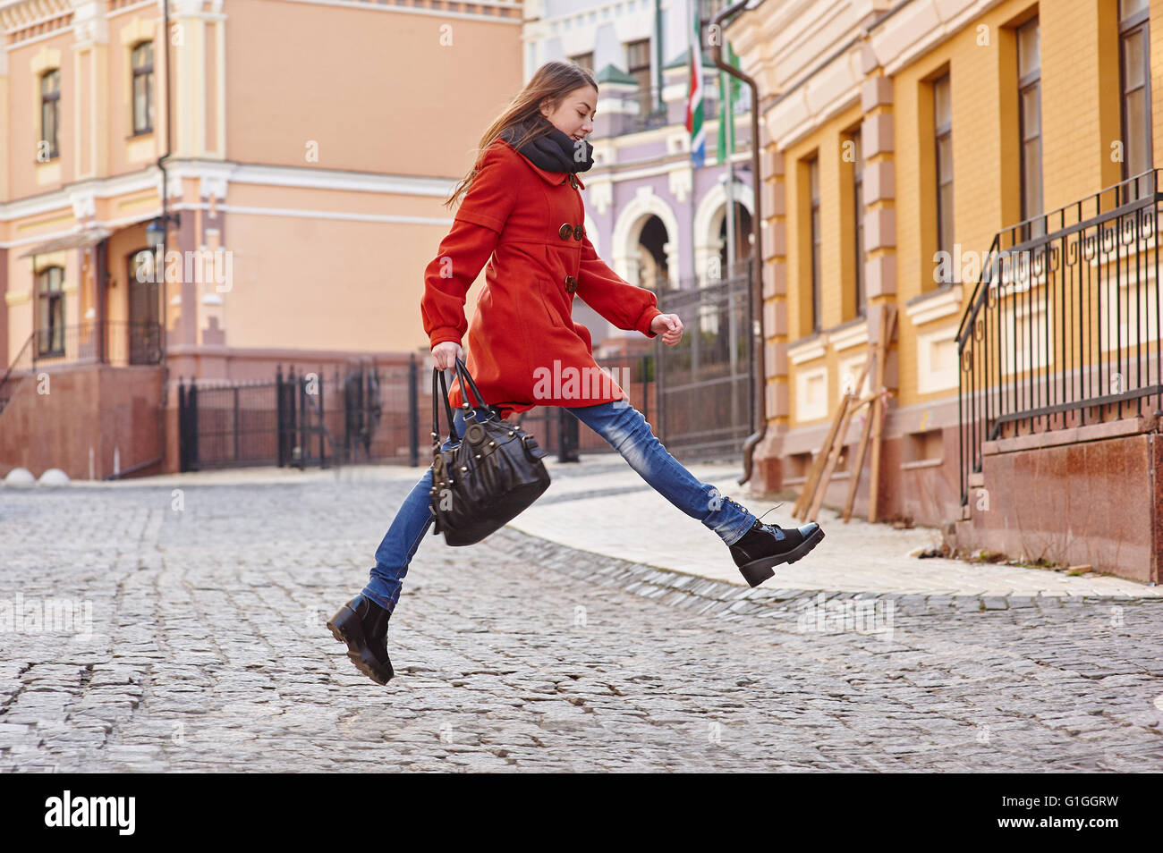 junge schöne Frau im roten Mantel in der Stadt Stockfoto