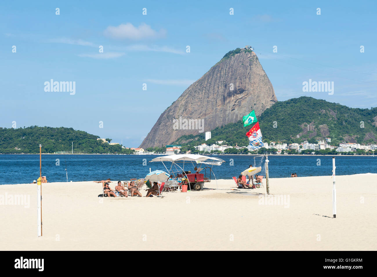 RIO DE JANEIRO - 5. April 2016: Beachgoers versammeln sich am Strand von Flamengo unter einen malerischen Blick auf den Zuckerhut. Stockfoto