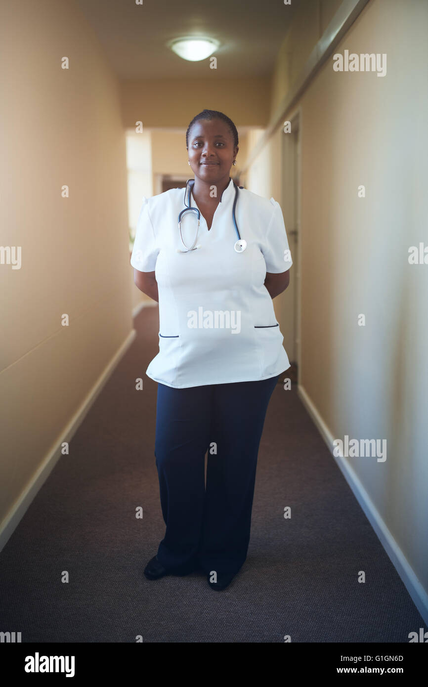 In voller Länge Portrait von Ärztin Krankenschwester stehen im Korridor des Pflegeheims. Fürsorgliche Krankenschwester Blick auf Kamera und smil Stockfoto