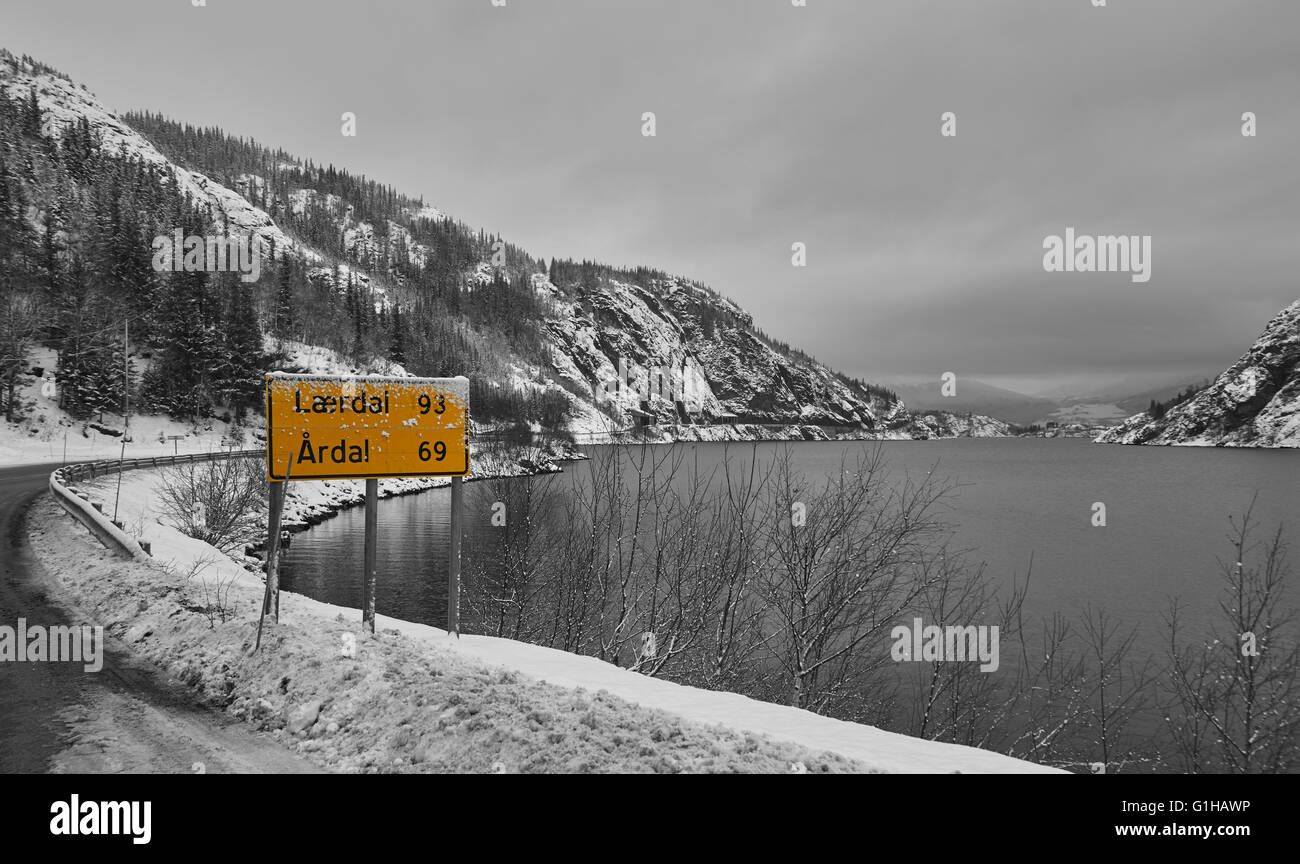 Ein gelbes Schild zeigt Abstand zu beiden Städten am Ufer des lakey an einem grauen, bewölkten Tag. Stockfoto