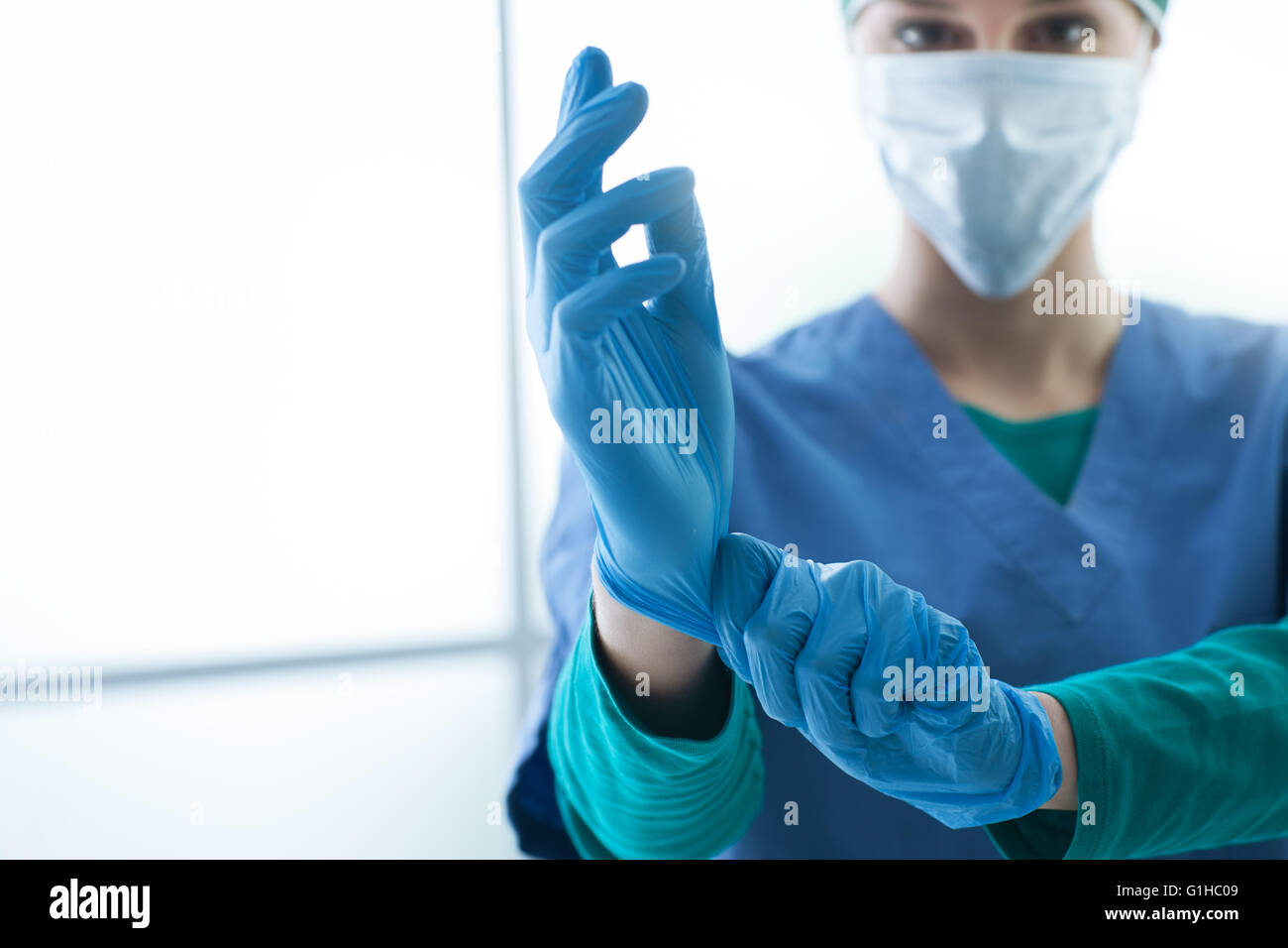 Weibliche Chirurg vorbereiten des chirurgischen Eingriffs, trägt sie Handschuhe und Blick in die Kamera, Gesundheitswesen und Vorbereitung con Stockfoto