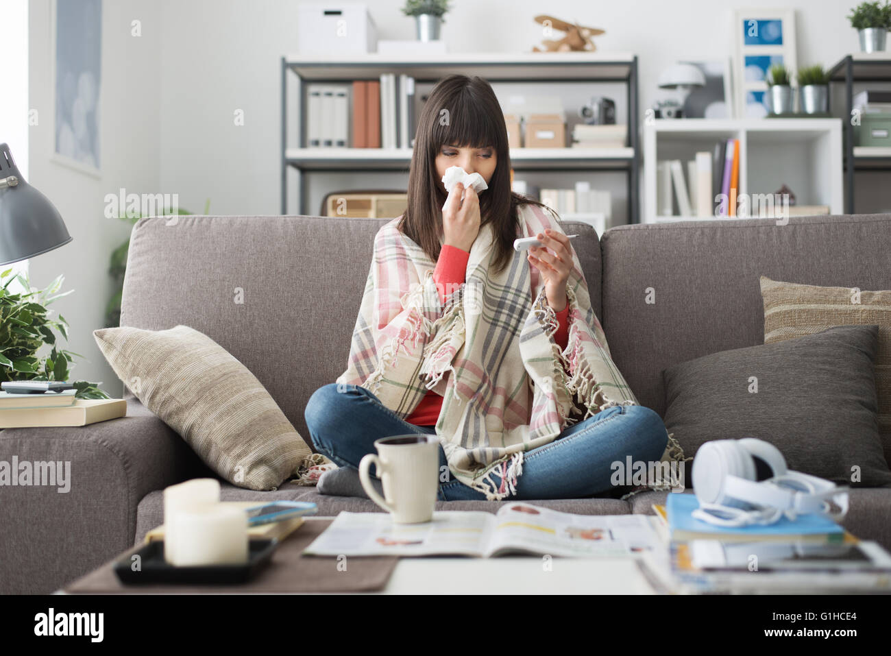 Kranke Frau mit Erkältung und Grippe, ruht sie auf dem Sofa zu Hause und Messung der Körpertemperatur mit einem thermometer Stockfoto
