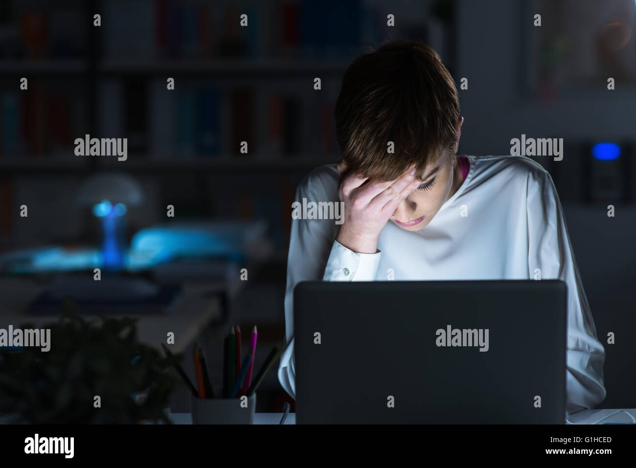 Müde Frau spät in die Nacht arbeiten sie einen Laptop verwenden und berühren ihre Stirn, Stress und Termine Konzept Stockfoto