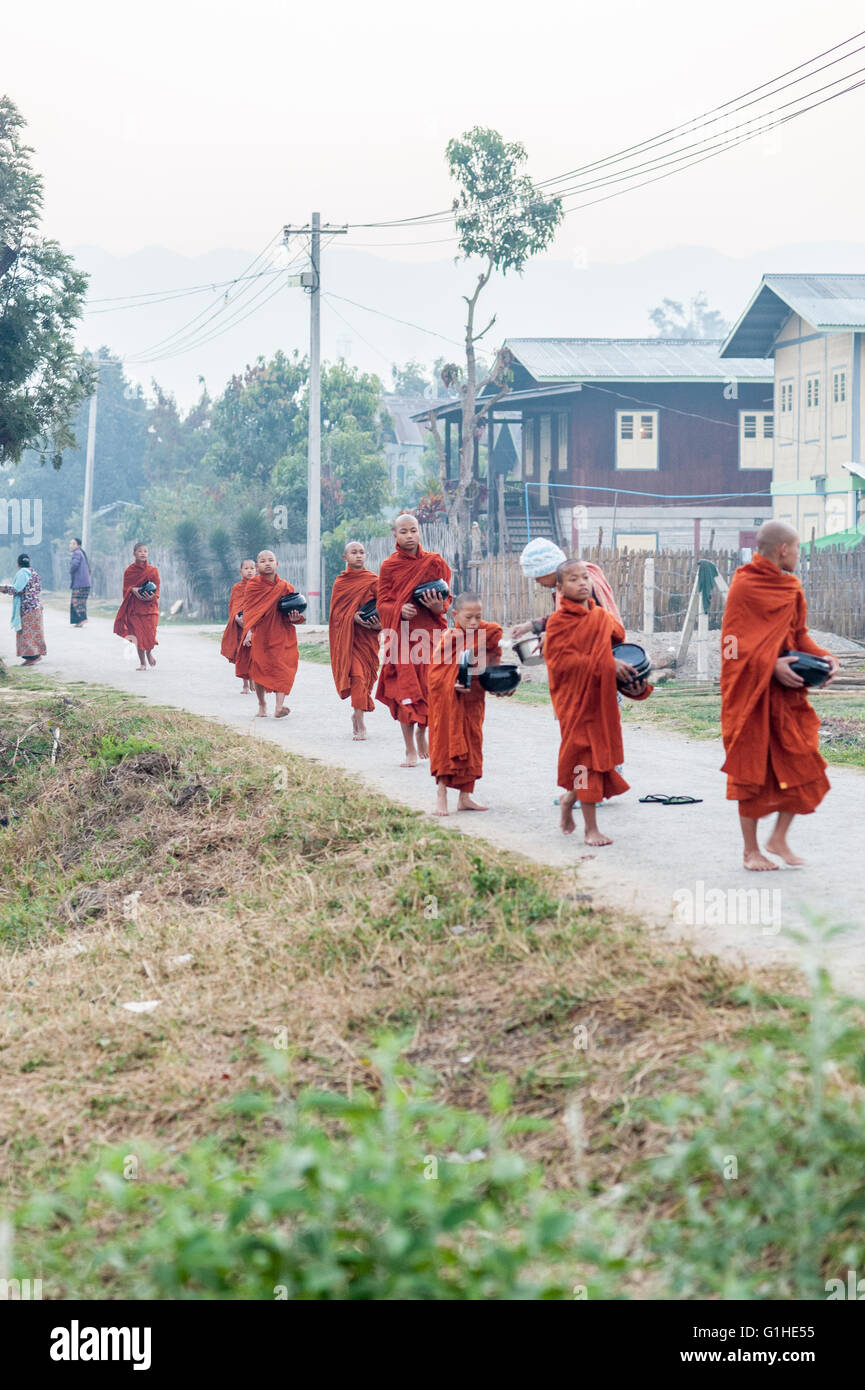 Die jungen Burmesischen buddhistischen Mönchen auf einem Morgen Reis sammeln Ritual. Die Mönche gehen auf die Straße. Barfuß buddhistische Mönche wandern. Stockfoto