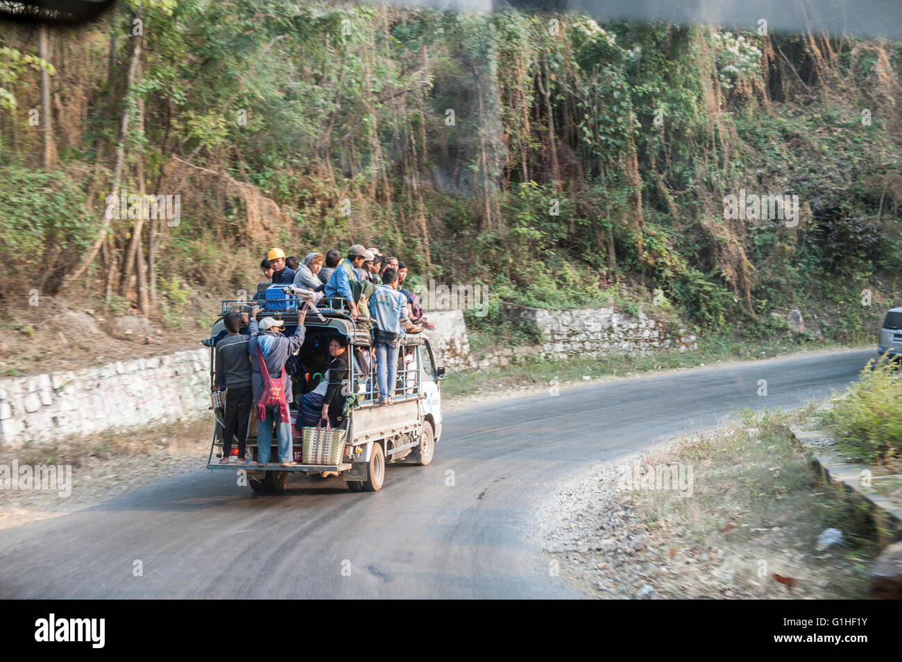 Ein LKW voll mit Arbeitern absteigend die windige Straße im Norden von Myanmar. Stockfoto