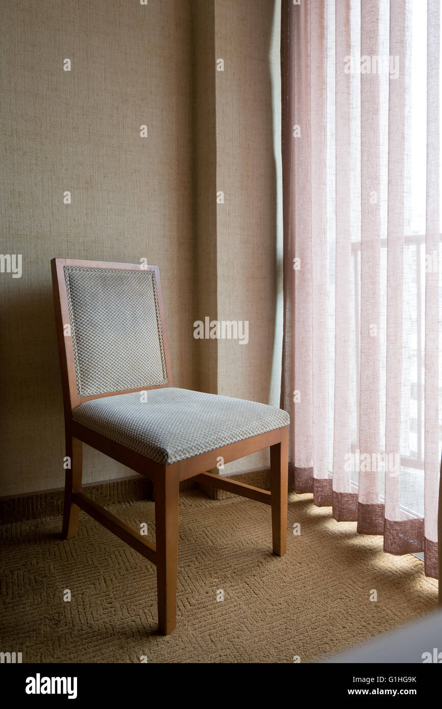 Stuhl sitzen am Fenster mit Vorhang im Zimmer. fühlen Sie sich einsam. Stockfoto