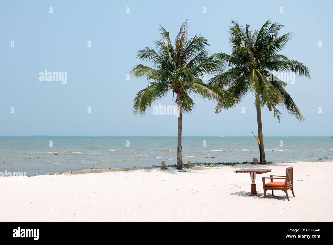 Stuhl und Tisch auf den weißen sauberen Sandstrand mit Kokospalmen und Meer gesetzt. Stockfoto