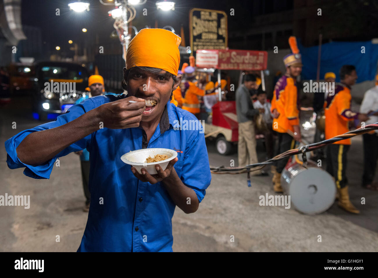 Junger Mann mit einem Snack, Bhagat Namdevs Geburt Sikh Festschrift Parade, Hyderabad Stockfoto