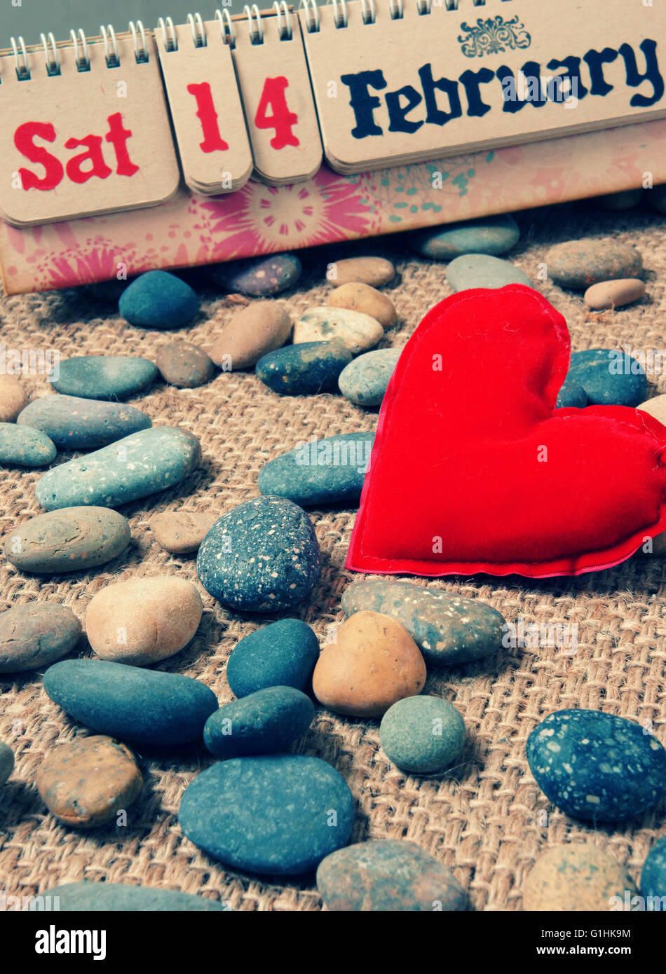 Rotes Herz, Symbol der Liebe mit Tischkalender, Feb 14 am schönen Kiesstrand, Faser-Hintergrund mit Vintage Farbe, Valentinstag Stockfoto