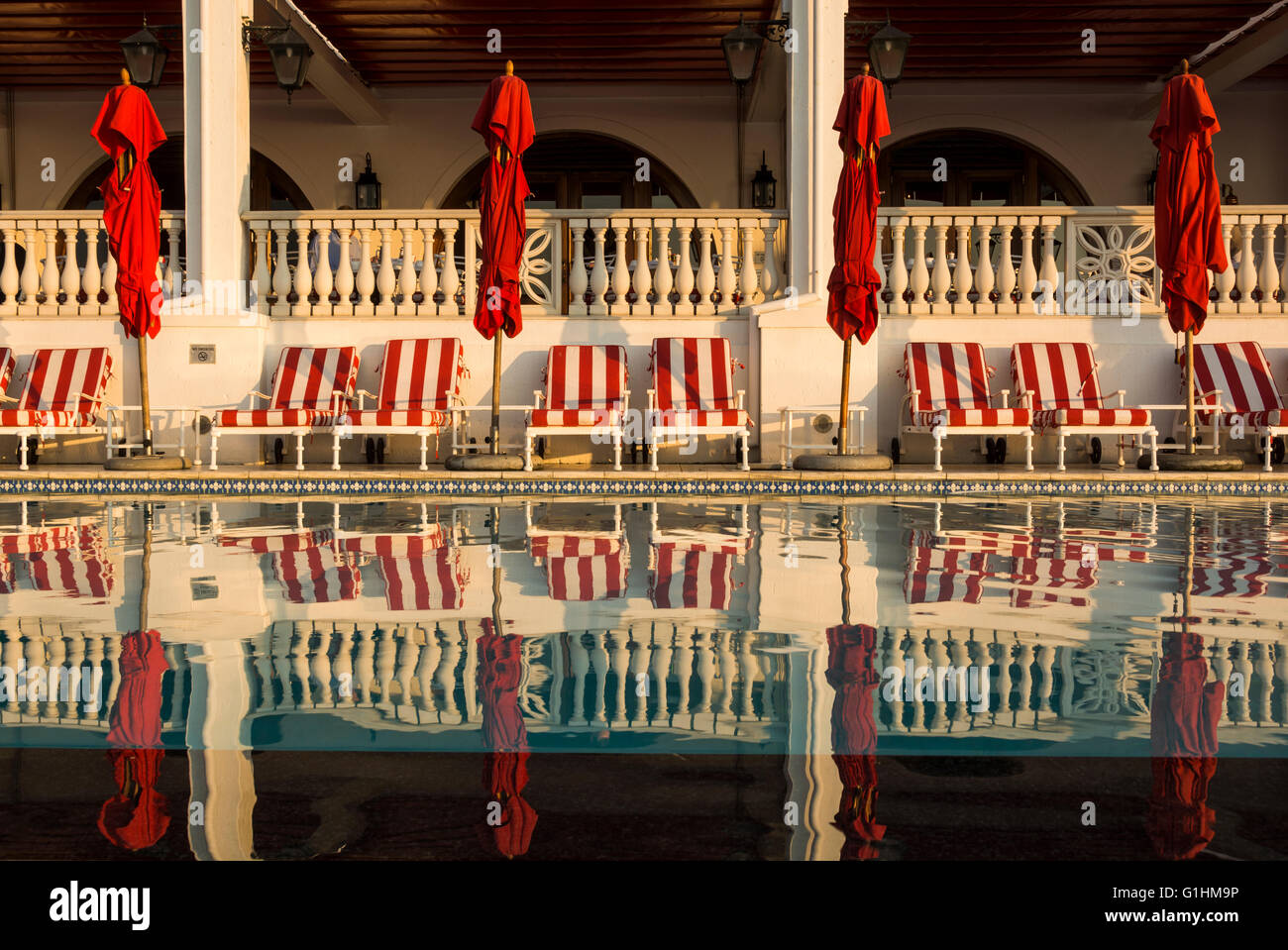 Sonnenliegen und rote Sonnenschirme warten auf Gäste am Pool eines Luxus-Hotels in Durban, KwaZulu Natal, Südafrika Stockfoto