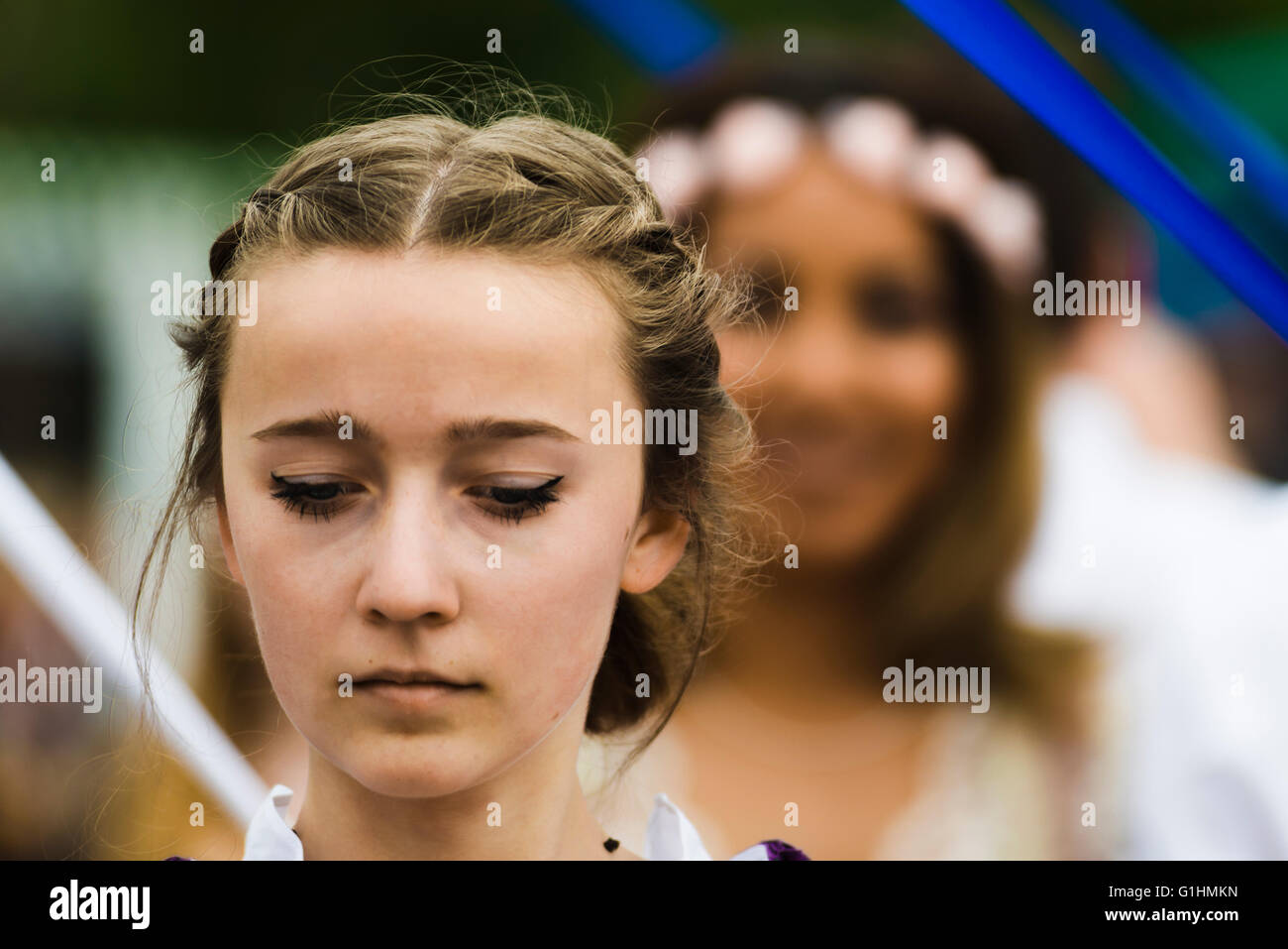 Porträt einer jungen Frau auf der Suche nach unten beim Tanzen eines traditionellen Volkstanzes um einen Maibaum, Bayern, Deutschland Stockfoto