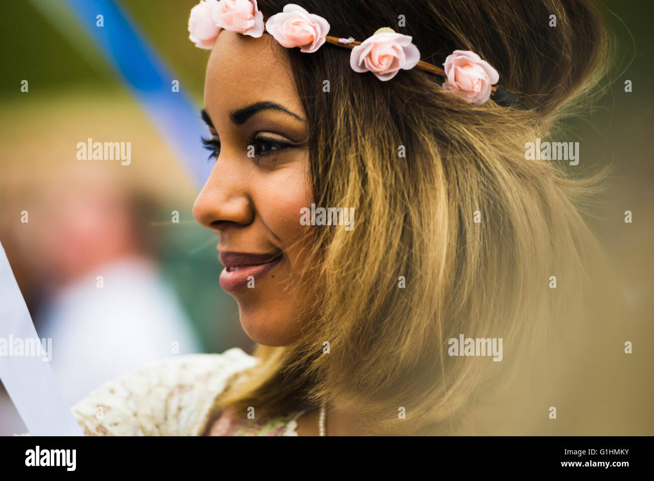 Porträt einer lächelnden dunkelhäutige Junge Frau mit einem Haarreif in einer traditionellen bayerischen Volkstanz um einen Maibaum Stockfoto