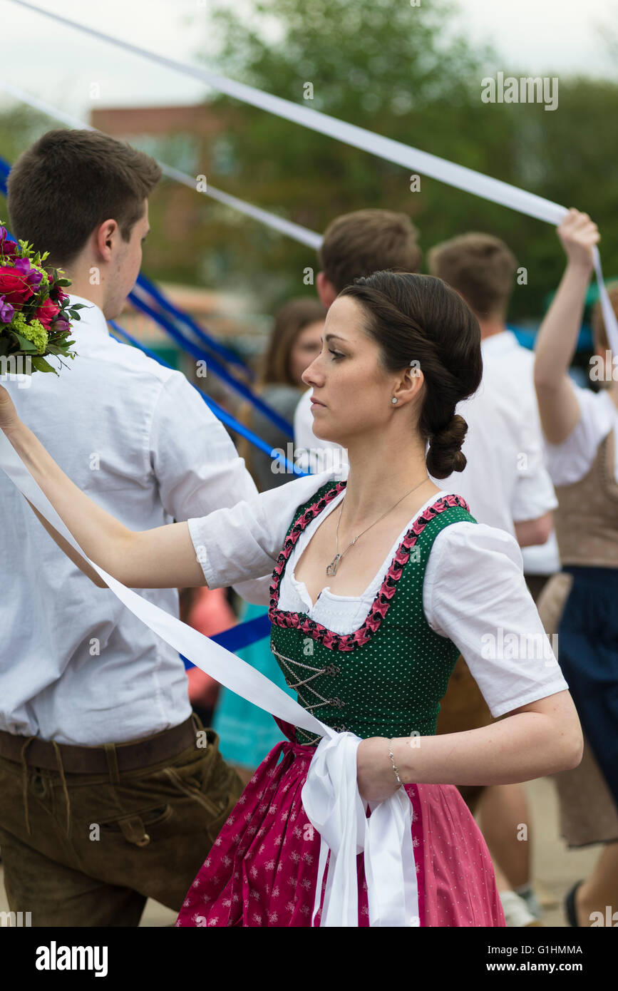 Porträt der jungen Frau in einem Kleid, einen traditionellen bayerischen Volkstanz um einen Maibaum mit einem weißen Band und Blumen tanzen Stockfoto