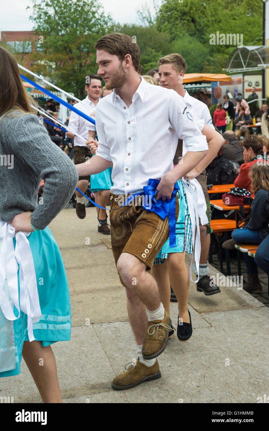 Porträt des jungen Mann in weißem Hemd und Lederhosen tanzen einen traditionellen bayerischen Volkstanz Bandltanz um einen Maibaum Stockfoto