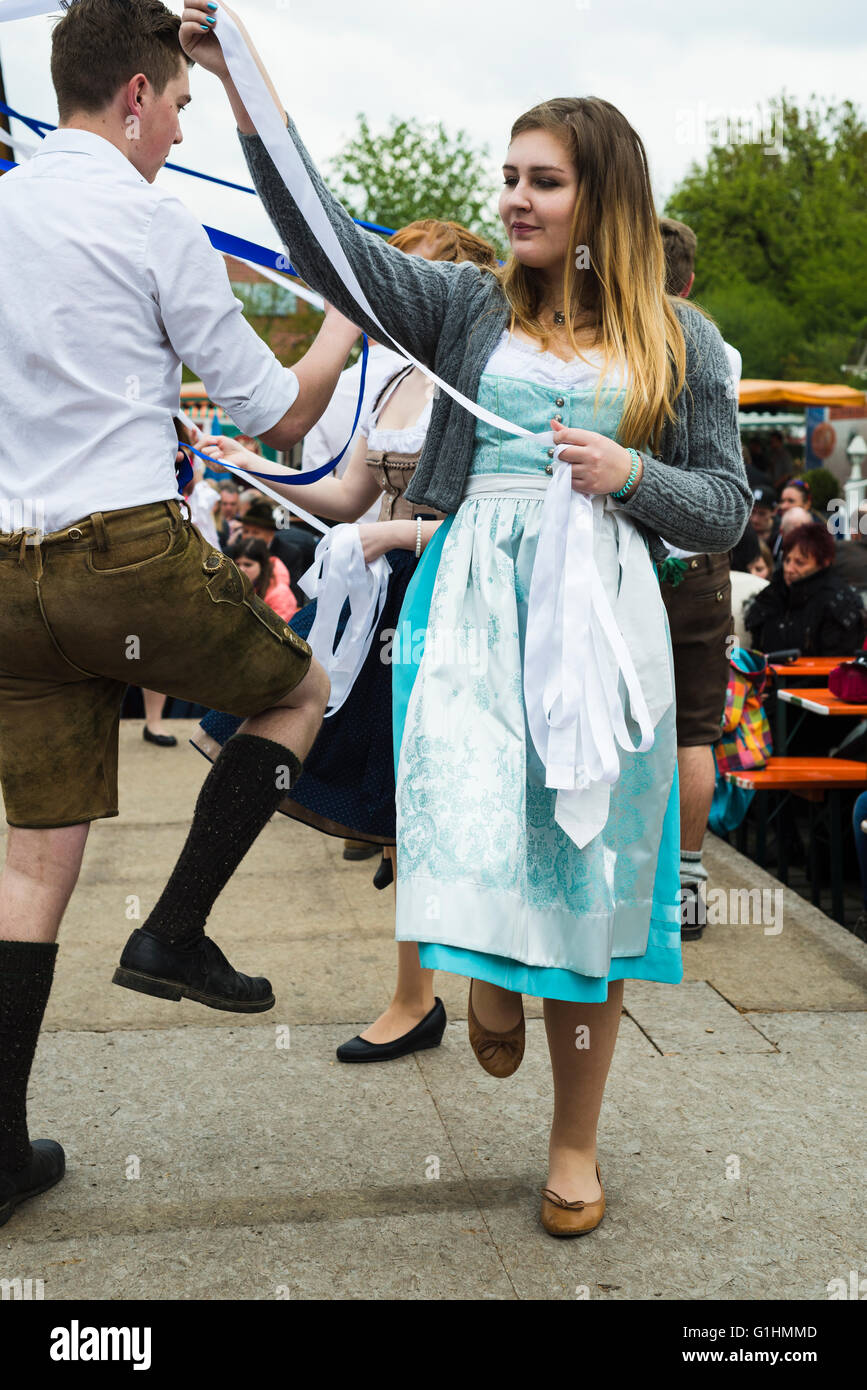 Porträt einer jungen Frau und Mann in lokalen Kleid und Lederhosen tanzen einen traditionellen bayerischen Volkstanz halten Bänder Stockfoto