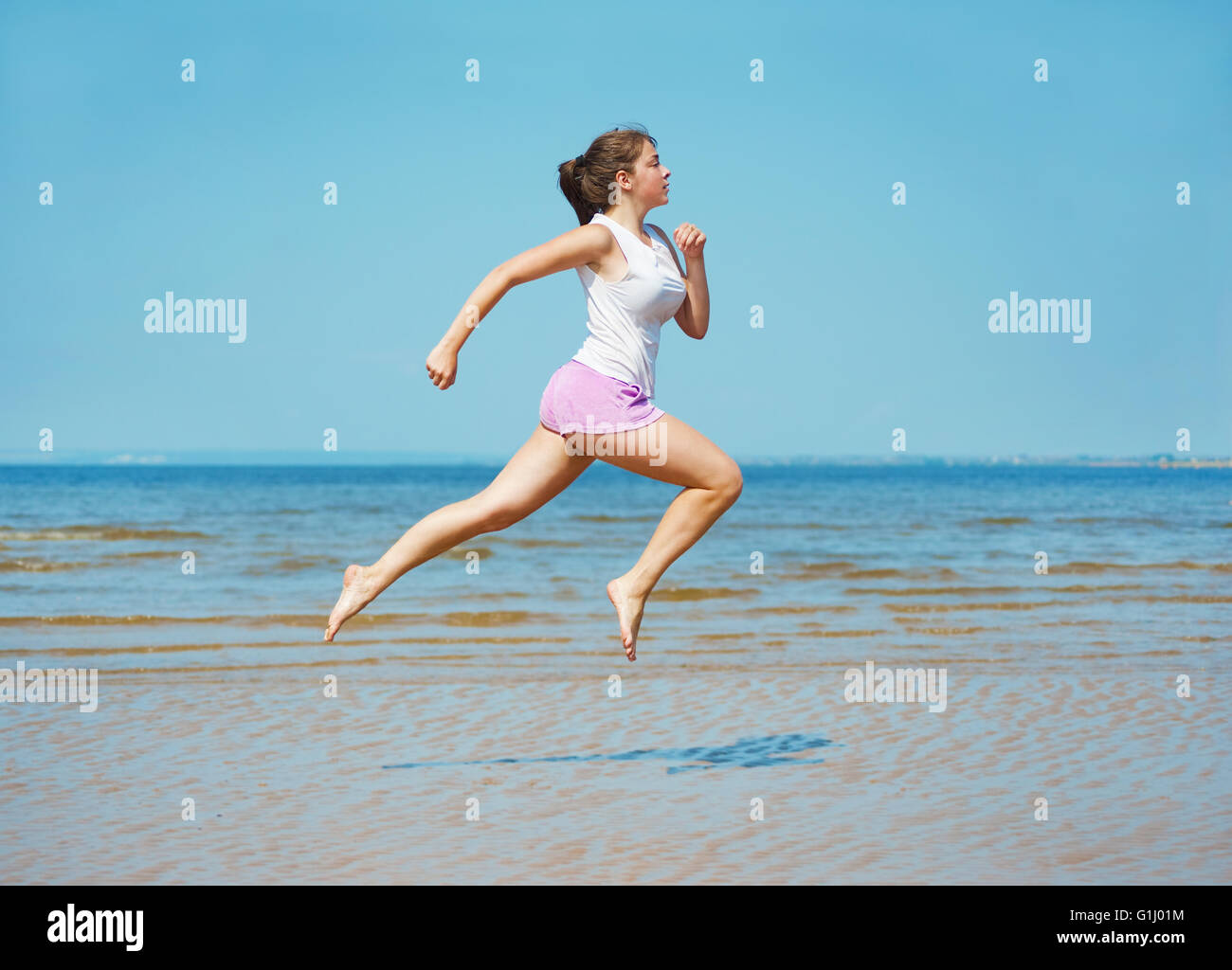 Attraktive junge Frau läuft alleine am Strand Stockfoto