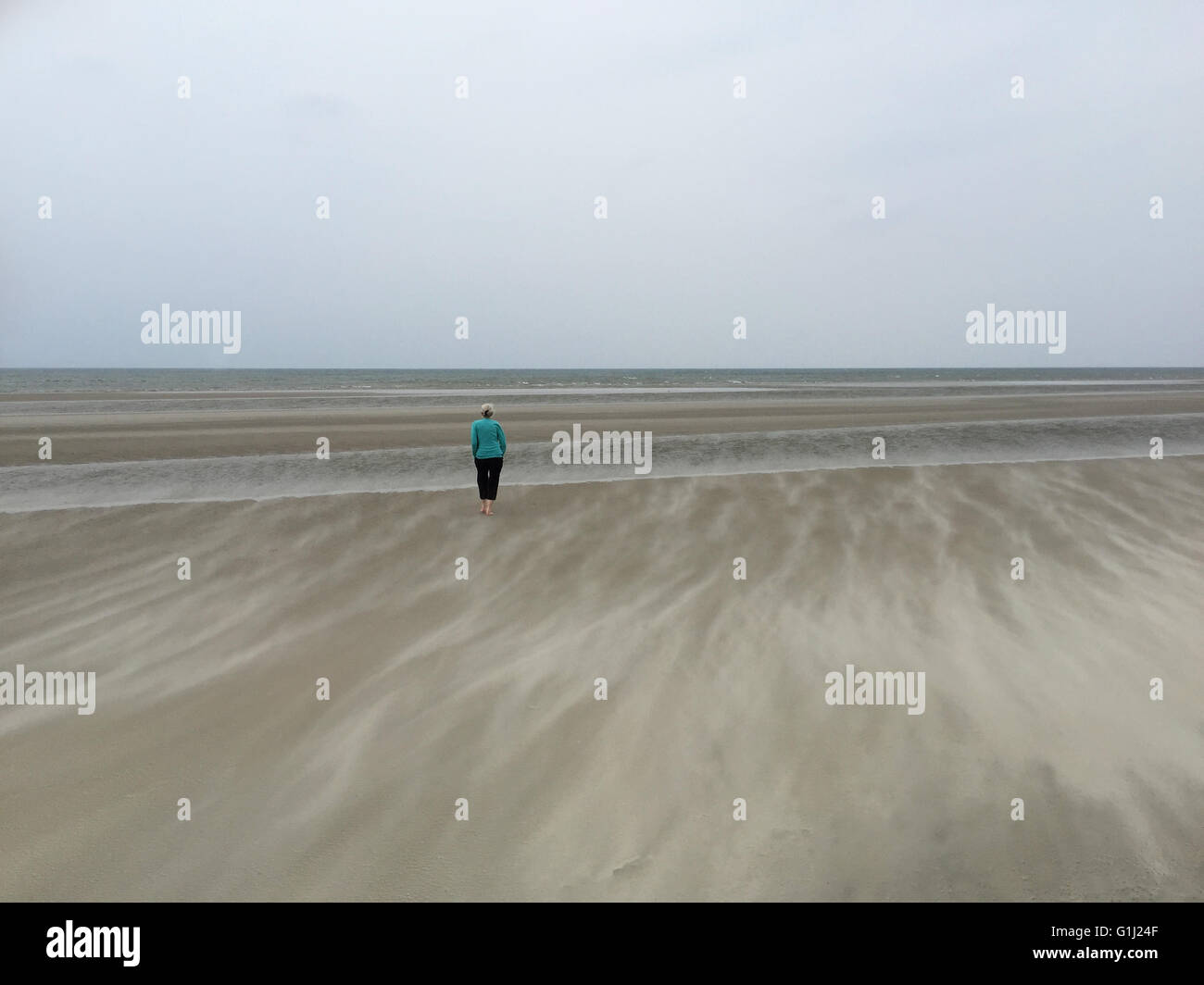 Ältere Frau am Strand in Sandsturm, Fanoe, Jütland, Dänemark Stockfoto