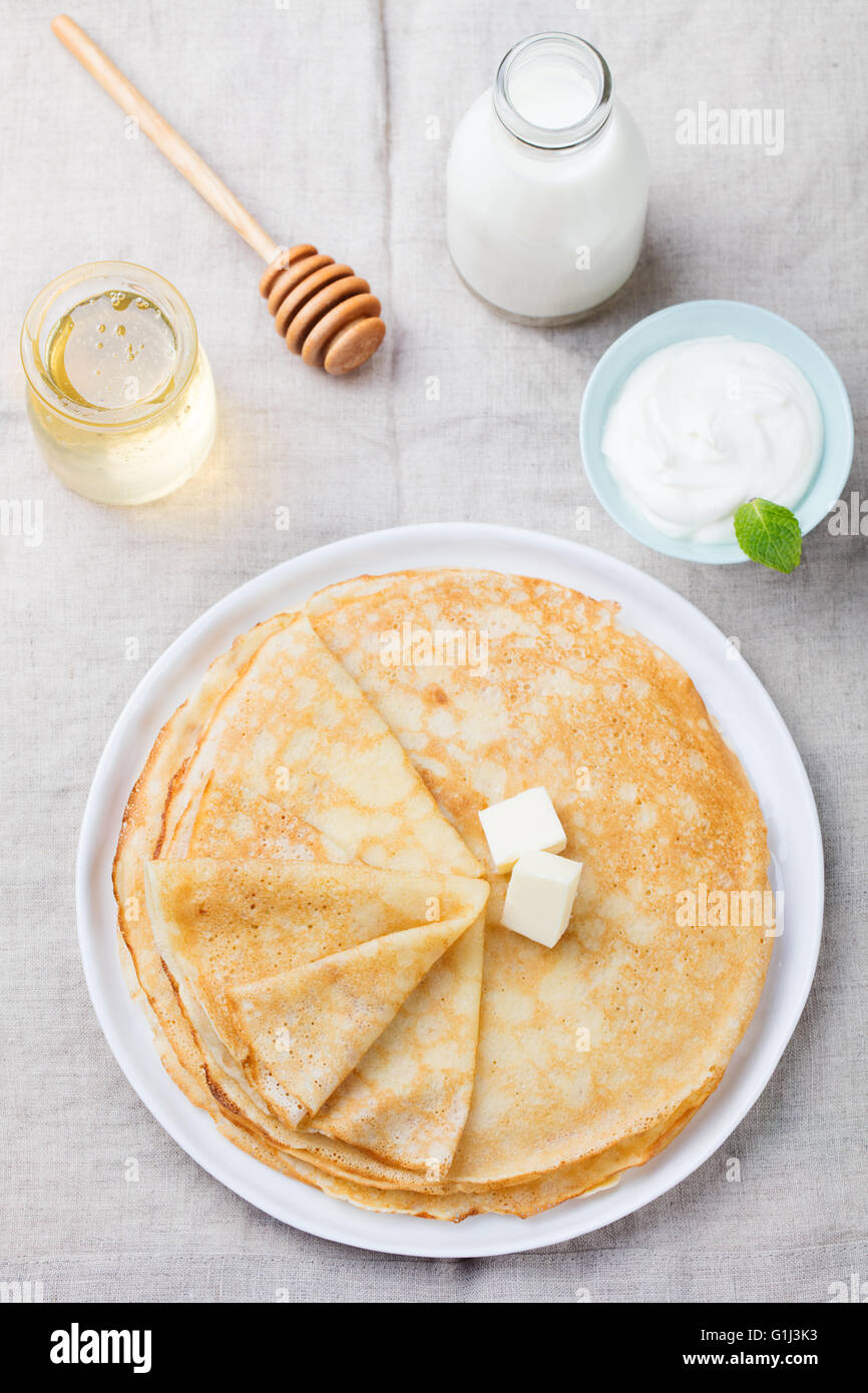 Dünne Crêpes oder Pfannkuchen mit Butter, Honig und Sauerrahm in einer ...