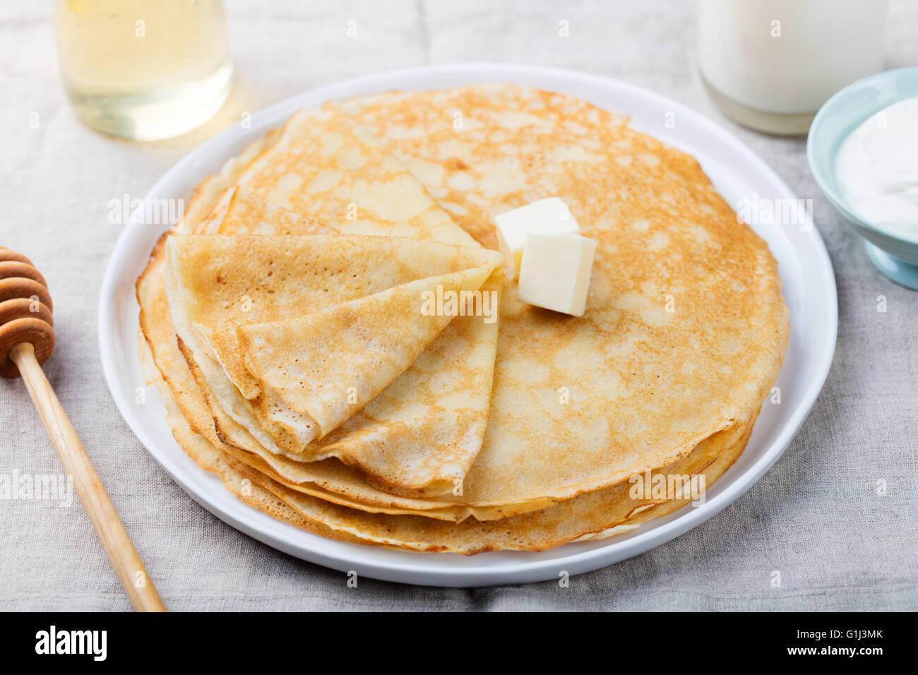 Dünne Crêpes oder Pfannkuchen mit Butter, Honig und Sauerrahm auf einem ...