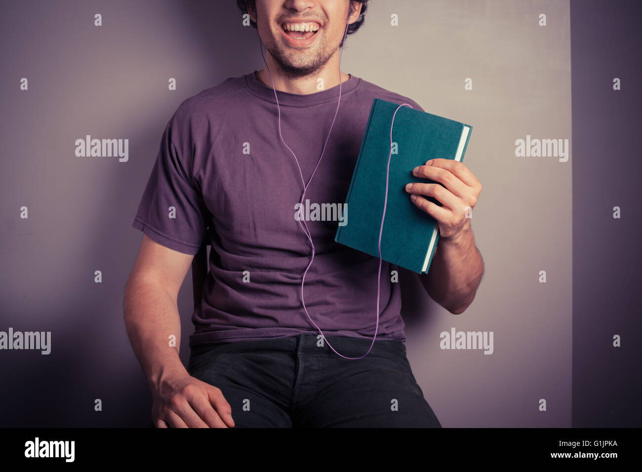 Ein glücklicher junge Mann ist ein Audiobuch hören Stockfoto