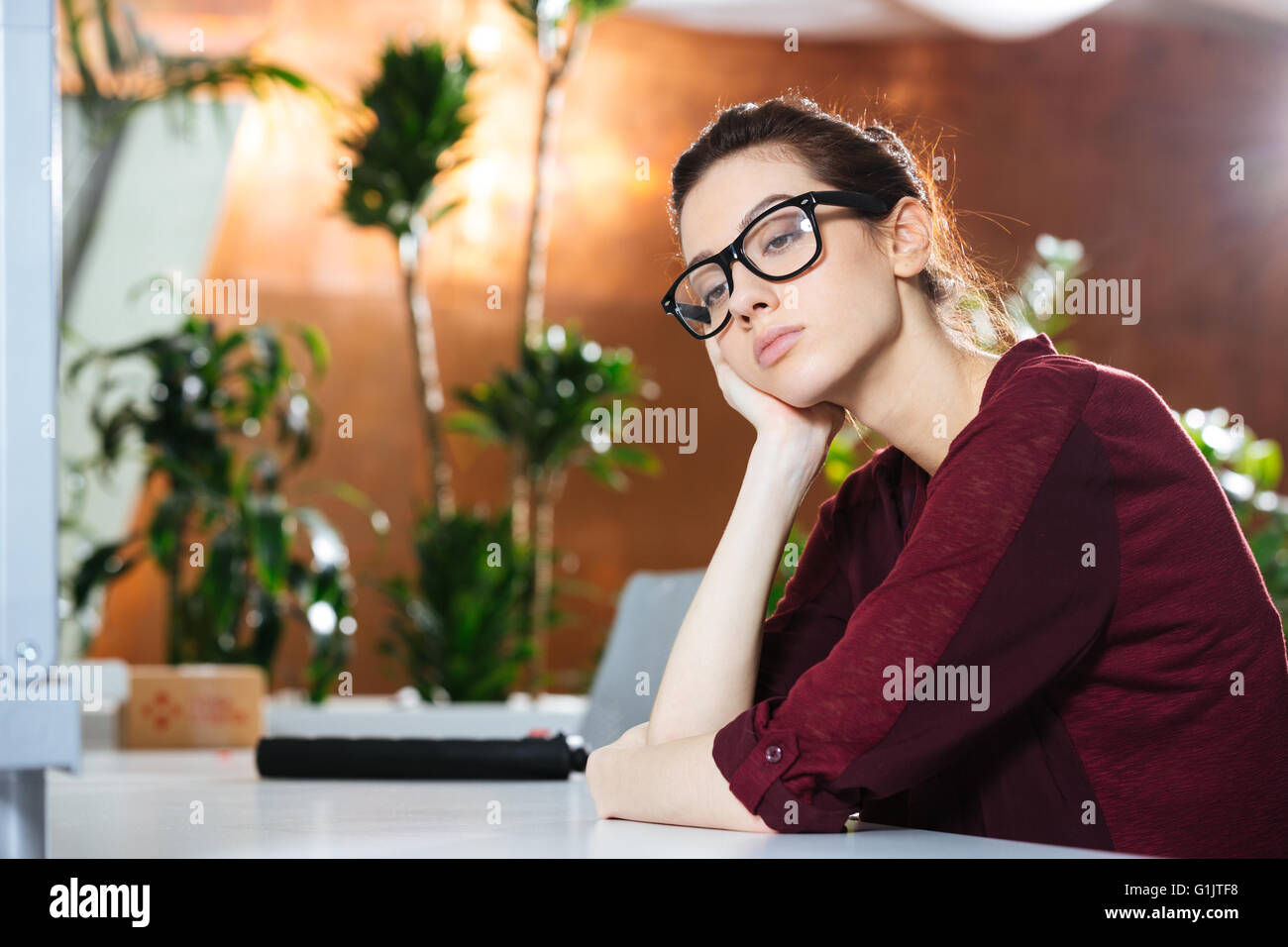 Unglückliche schöne junge Geschäftsfrau in Gläsern im Büro sitzen Stockfoto