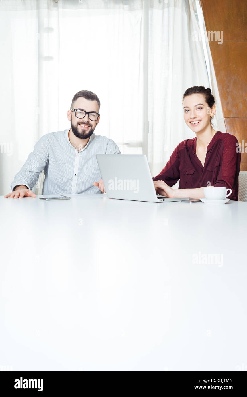 Porträt zweier lächelnd attraktive junge Geschäftsleute am Tisch sitzen und mit Laptop im Tagungsraum Stockfoto