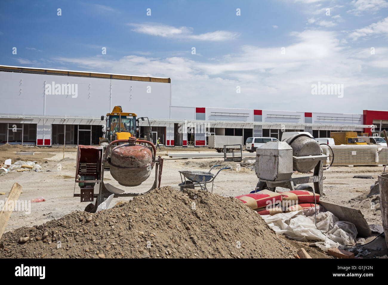 Betonmischer-Maschine bei Bau-Website, Werkzeuge, Sand und Zement-Tasche. Stockfoto