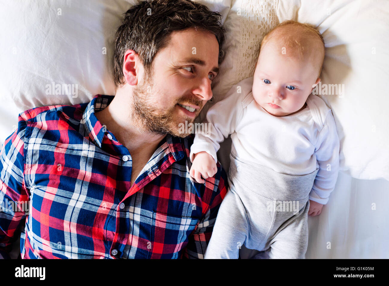Baby Boy auf Bett, neben seinem Vater Stockfoto