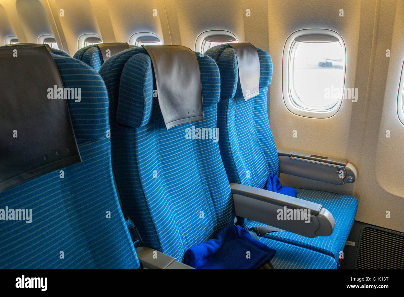 Blaue Beifahrersitz auf einem Passagierflugzeug durch Fenster Stockfoto