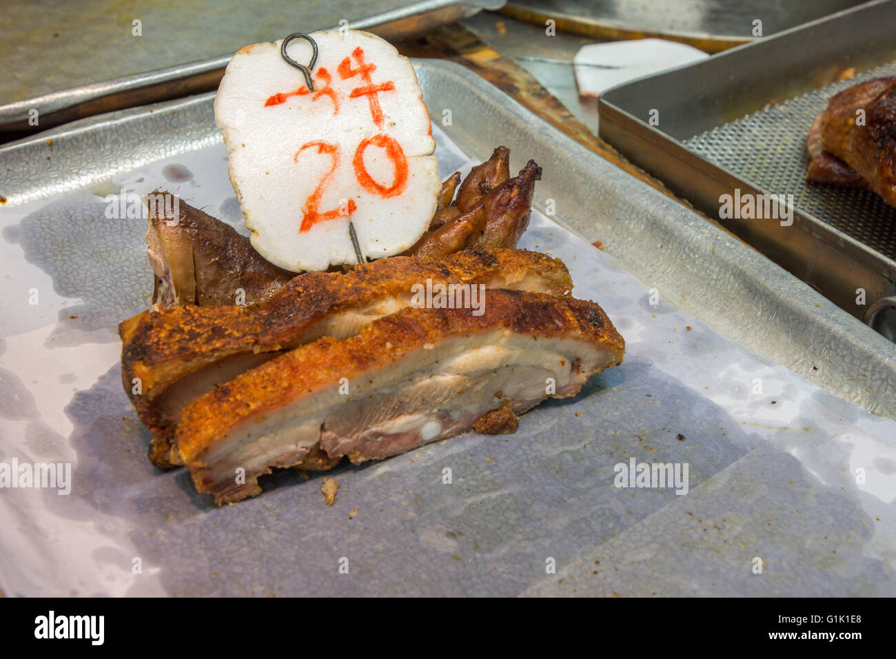 Schneiden Sie knusprig Schweinefleisch auf Metalltablett in chinesischen Garküche Stockfoto