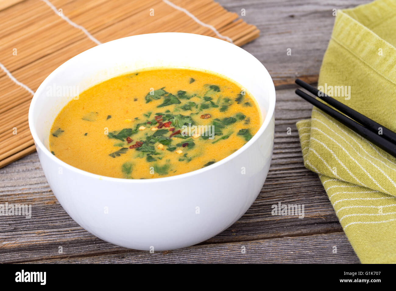 gelbes Thaicurry-Suppe mit Koriander auf rustikalen Tisch Stockfoto