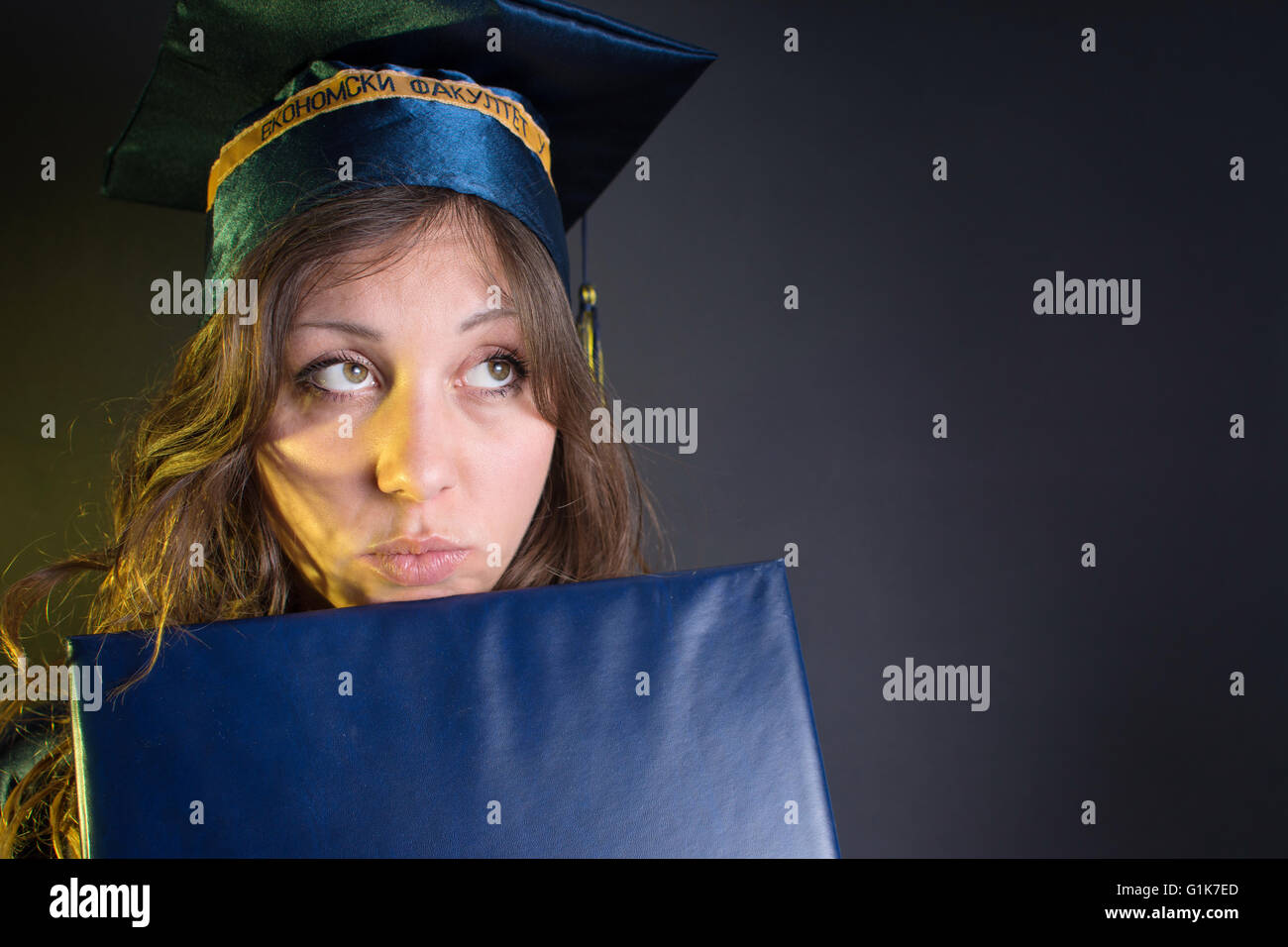 Brünettes Girl mit einem Diplom in Promotion Kostüm und Hut Stockfoto