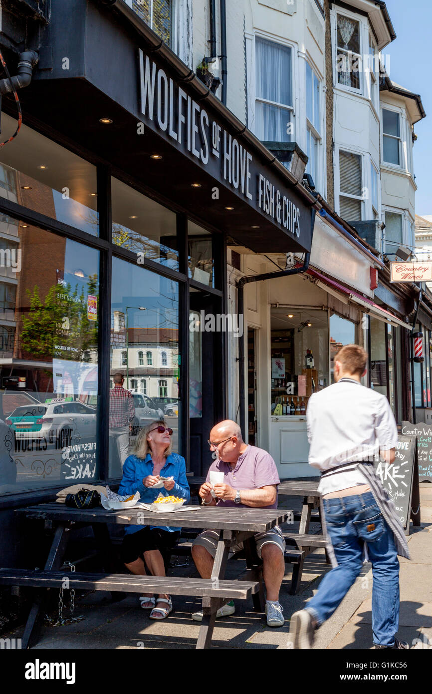 Ein applying paar Essen Fish And Chips außerhalb Wolfies Fisch und Chips-Shop, Hove, Sussex, UK Stockfoto